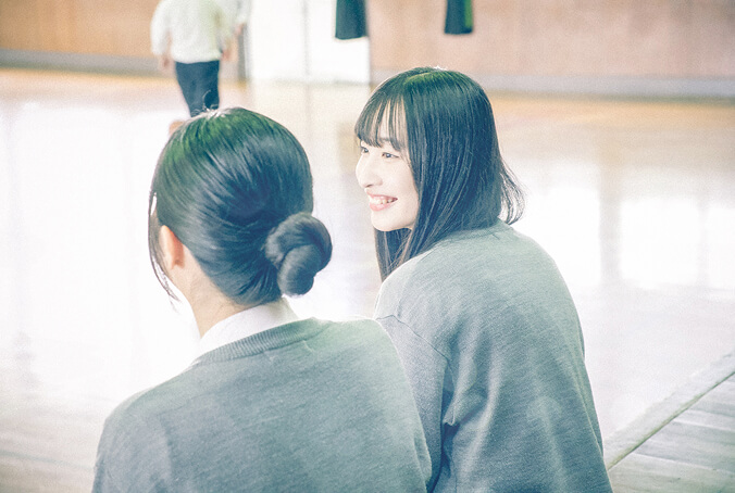 体育館で女子生徒が2人並んで話している写真です。