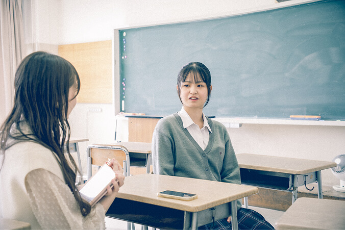 ライターと在校生3人が向かい合って座っている写真です。和やかにインタビューを受けています。