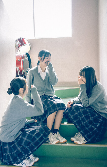 階段で談笑する3人の生徒の写真です。
