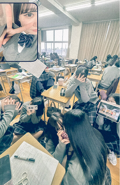 教室内でたくさんの生徒が一緒に写真を撮っています。