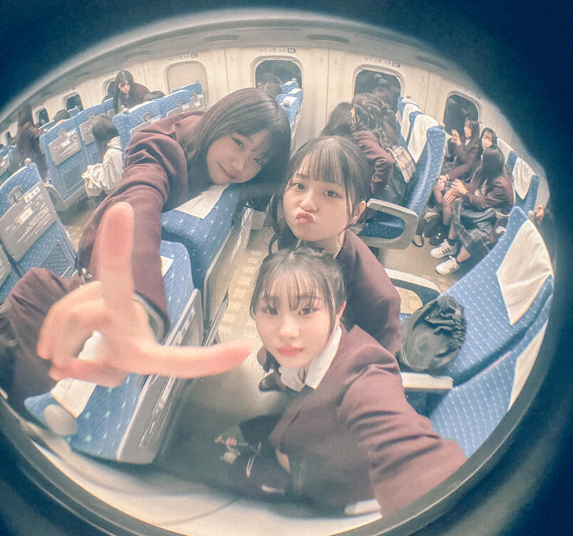新幹線の車内。3人で自撮りをする女子生徒の写真です。